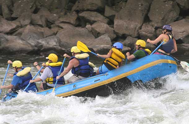 Group of people white water rafting in yellow helmets and life jackets